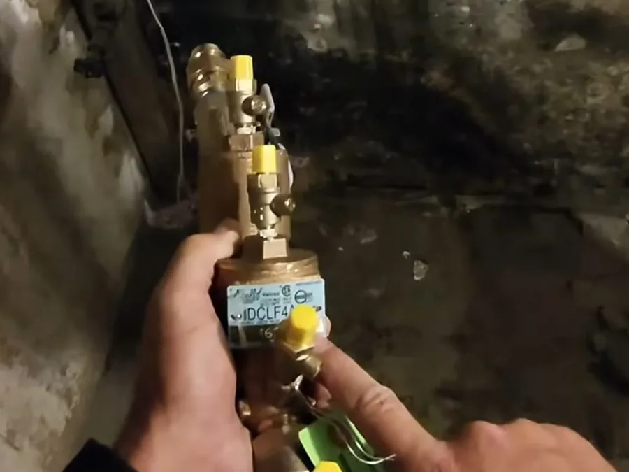 Gas shutoff valve held near an outdoor appliance connection