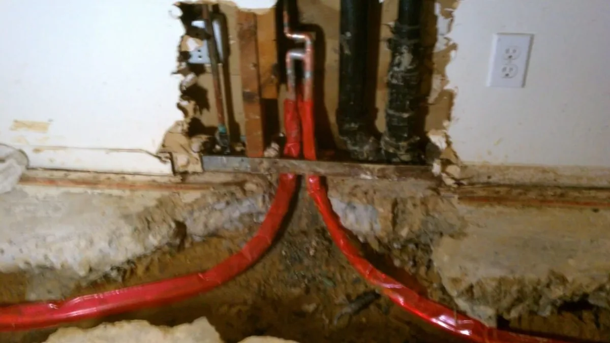 Red PEX supply lines routed through an open wall during repiping in South Pasadena