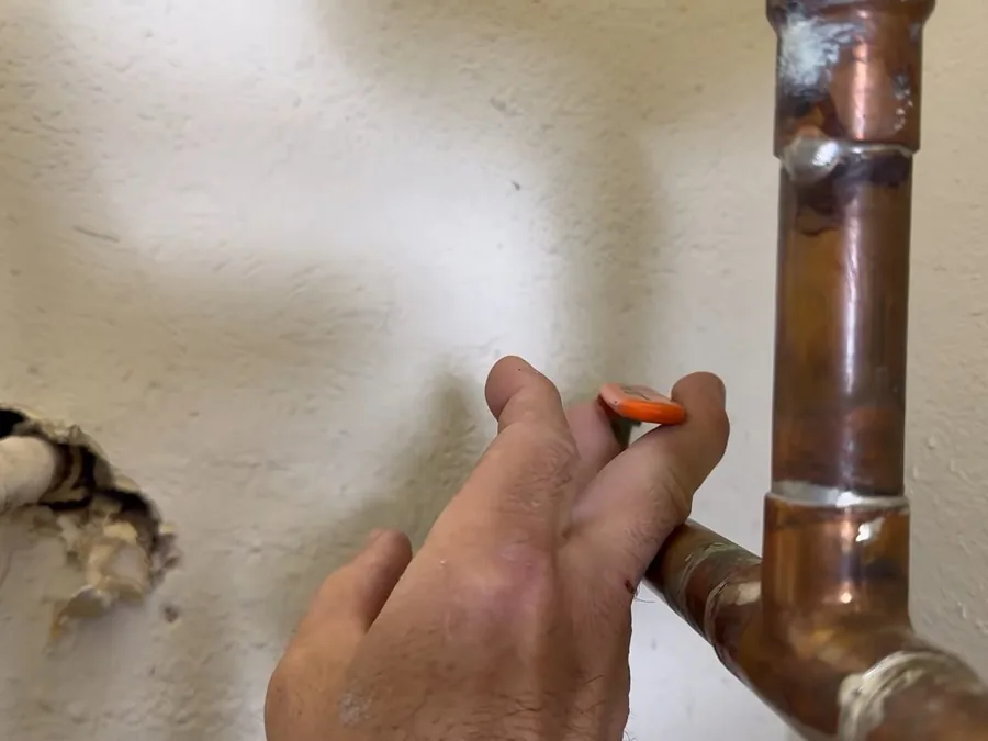 Anode rod being removed from the top of a tank water heater